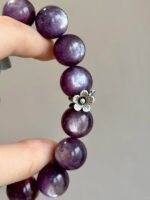 Lepidolite bracelet on wrist, silver charms match purple beads, water - metal energy shows vintage charm