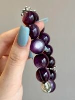 Close - up of lepidolite bracelet, silver charms twist with purple beads, water - metal energy hides starlight