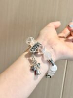 Multi-crystal bracelet on wrist, silver flower charm adds detail, metal-water energy builds ambient vibe