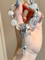 Close-up of multi-crystal bracelet, silver owl charm twists with crystals, metal-water energy hides protective meaning