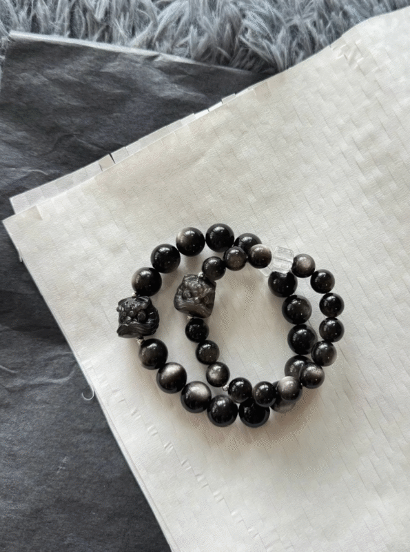 Flat lay of silver obsidian couple bracelets! Black - silver vibe + lion charm, perfect for edgy romance