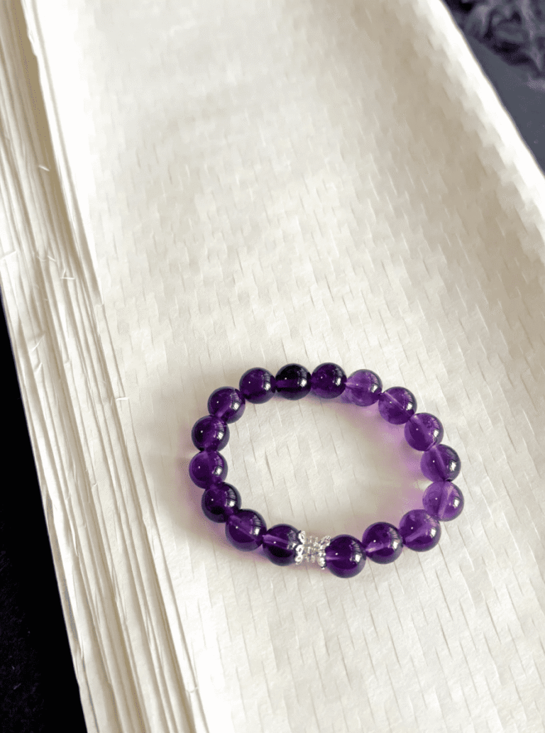 Gradient Uruguayan amethyst bracelet flatlay, deep-purple and light-purple twining silver, water-element energy hidden in luster