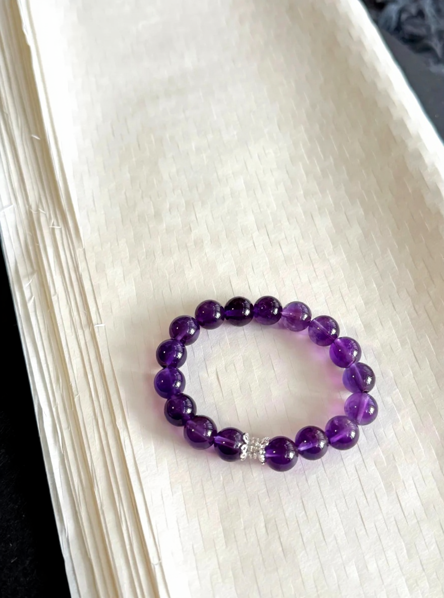 Gradient Uruguayan amethyst bracelet flatlay, deep-purple and light-purple twining silver, water-element energy hidden in luster