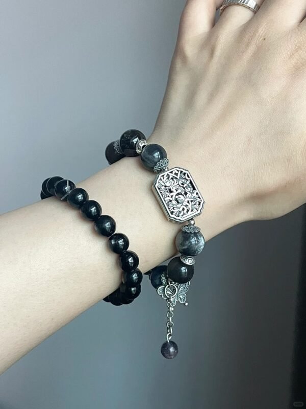 Vintage silver plaque bracelet on wrist, black-gray stones with silver carvings, earth-water-metal energy hidden in knots