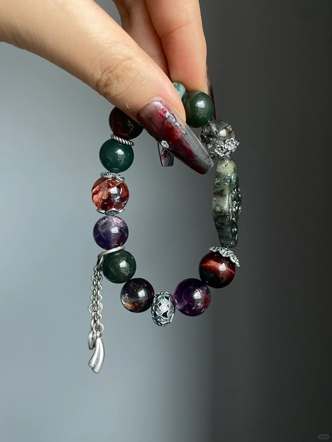 Holding Jiangzi bracelet with tassel, red rutile & silver fringe, earth-fire-metal energy building aura