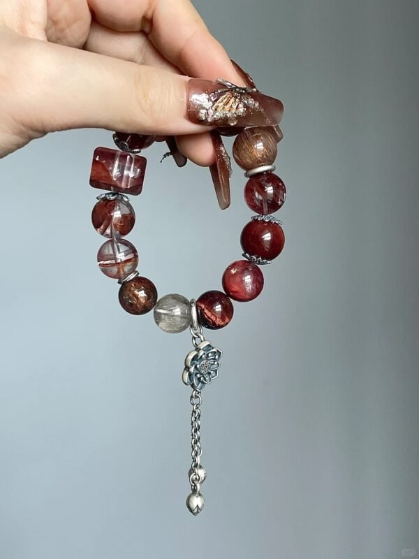 Holding red rutile bracelet with tassel, silver carvings & red tiger’s eye, fire-metal energy building aura