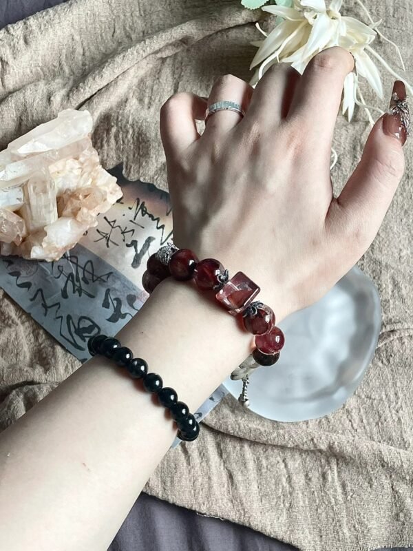 Red rutile bracelet on crystal tray, red hues highlighted, fire-metal energy showing intensity