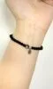 Obsidian bracelet on wrist, delicate bead design, water-metal energy building protection aura