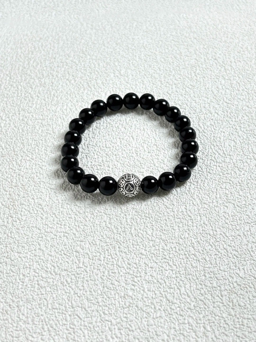 Close-up flatlay of obsidian bracelet, black beads matching silver, water-metal synergy hiding mystery