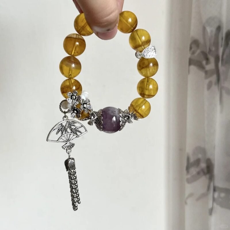 Close-up of golden rutilated quartz & purple rabbit hair bracelet, silver carvings match gems, metal-fire-earth energy in patterns