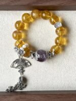Flatlay of Golden Rutilated Fluorite Bracelet, Purple Rabbit Hair & Silver Charms Mix, Earth-Metal-Water Energy Hides Wealth Code