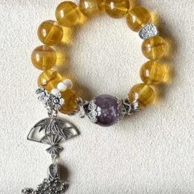 Flatlay of Golden Rutilated Fluorite Bracelet, Purple Rabbit Hair & Silver Charms Mix, Earth-Metal-Water Energy Hides Wealth Code