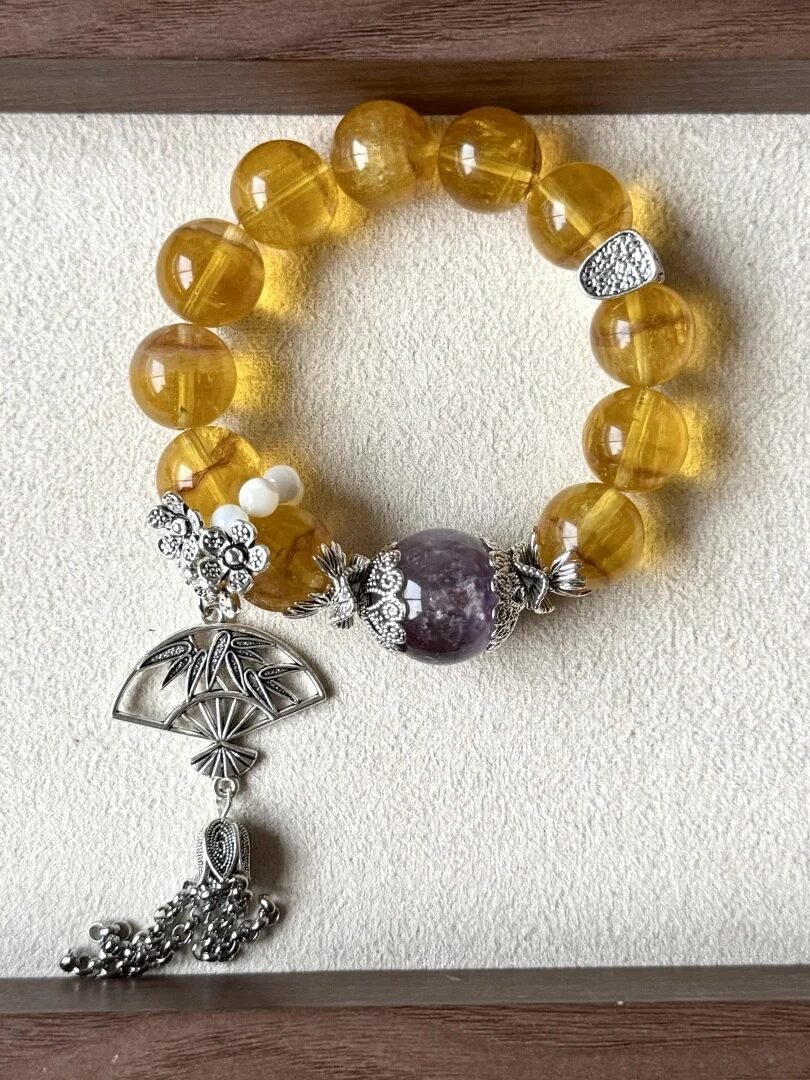 Flatlay of Golden Rutilated Fluorite Bracelet, Purple Rabbit Hair & Silver Charms Mix, Earth-Metal-Water Energy Hides Wealth Code
