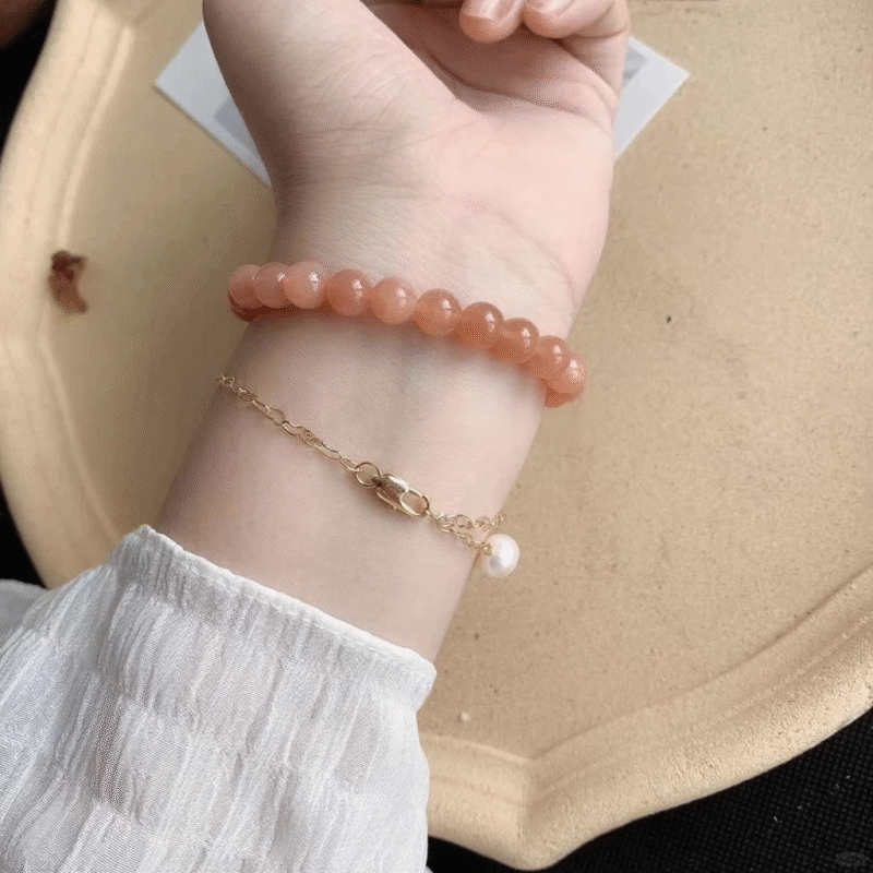 Layered orange moonstone bracelet with gold chain & pearl, fire-metal-earth energy builds elegance