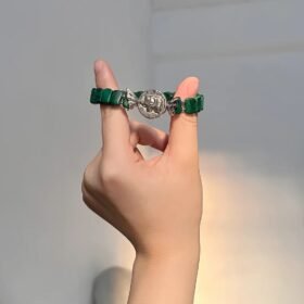 Malachite bracelet on finger, silver flower charm shows craft, wood-metal energy builds finger aura