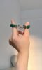 Malachite bracelet on finger, silver flower charm shows craft, wood-metal energy builds finger aura