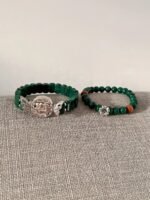Flatlay of double malachite bracelets, silver elephant & red agate match, wood-fire-metal energy shows vintage style