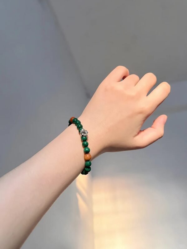 Single malachite bracelet on wrist, green beads show warmth, wood-fire-metal energy calms the mind
