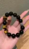 Hand Displaying 12mm Black Obsidian & Yellow Tiger’s Eye Bracelet, Water-Metal-Earth Energy Clashes Protection & Courage Field
