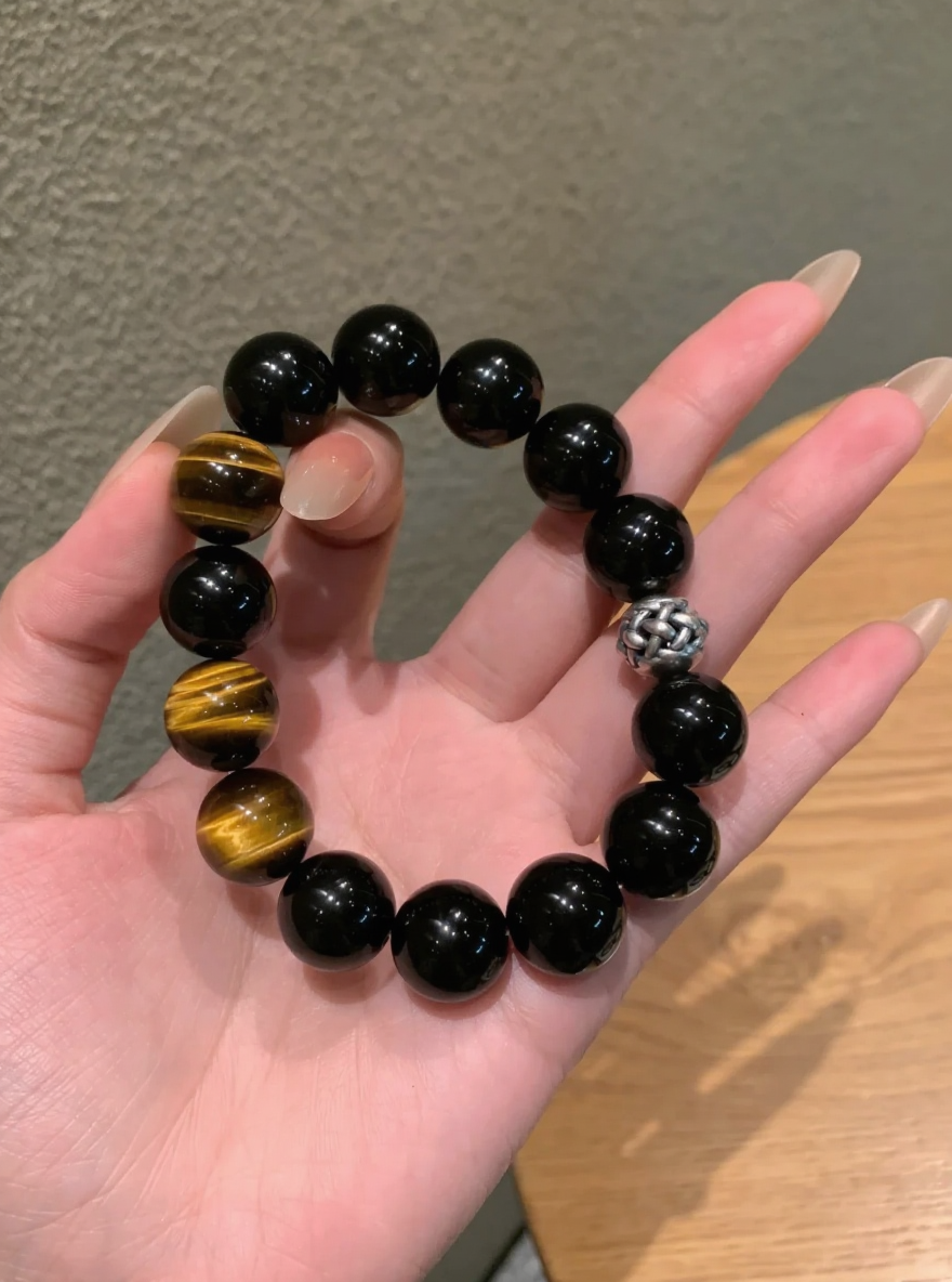 Hand Displaying 12mm Black Obsidian & Yellow Tiger’s Eye Bracelet, Water-Metal-Earth Energy Clashes Protection & Courage Field
