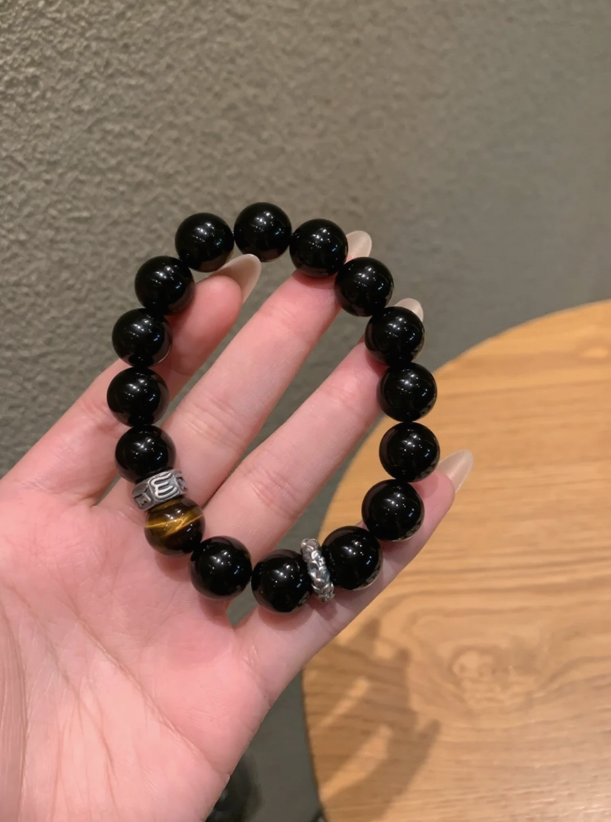 Hand Displaying 10mm Black Obsidian & Yellow Tiger’s Eye Bracelet, Water-Metal-Earth Energy Weaves Courage Field