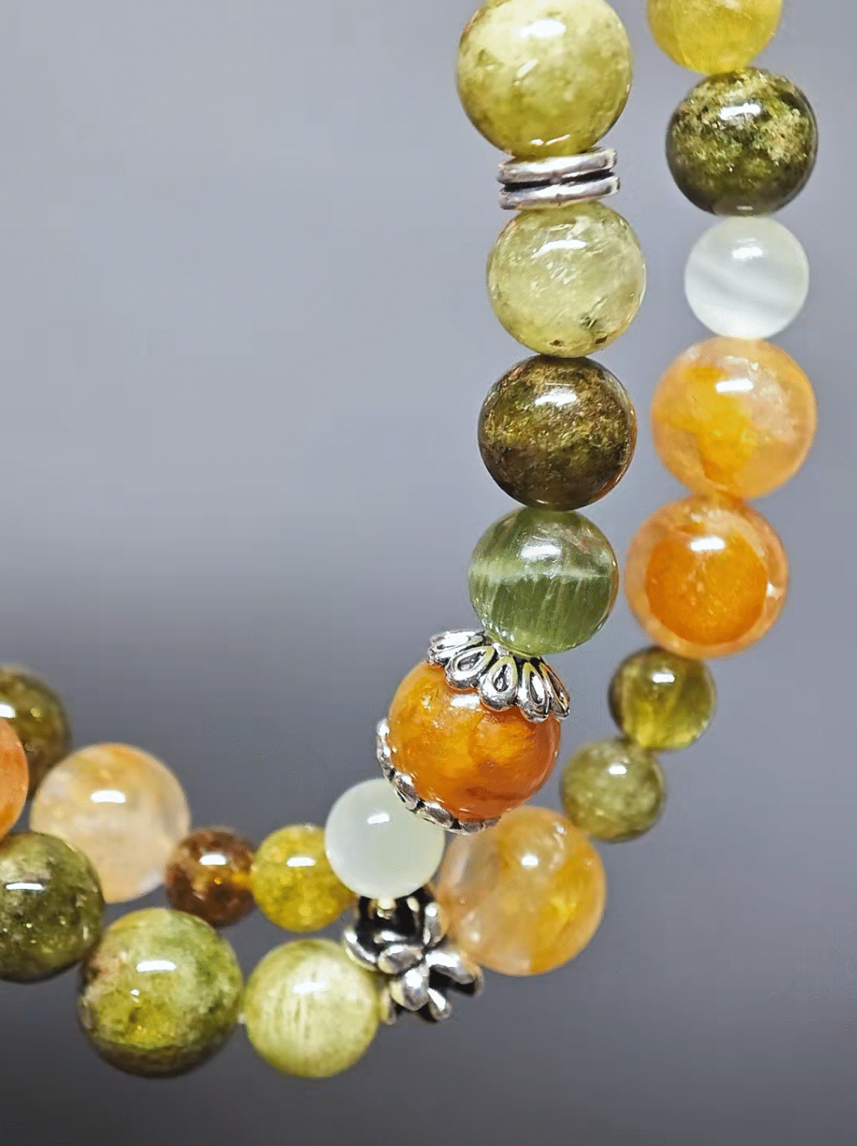 Multi-strand bracelet displaying color layers of Tsavorite Garnet, Yellow Fire Quartz, Xiu Jade, Hetian Jade, highlighting fire-earth synergy