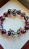 Design detail of Blood Red Fire Quartz bracelet, fire-metal protection of silver butterfly & rose