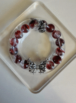 Close-up of Blood Red Fire Quartz bracelet, silver rose & butterfly totems, fire-metal energy resonance