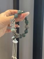 Design close-up of jadeite bracelet, silver totems resonating with beads, earth-metal harmony