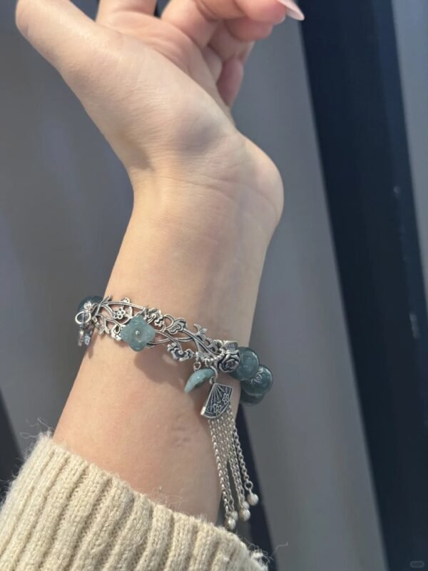 Wearing view of jadeite bracelet, silver fan tassel showcasing earth-metal charm