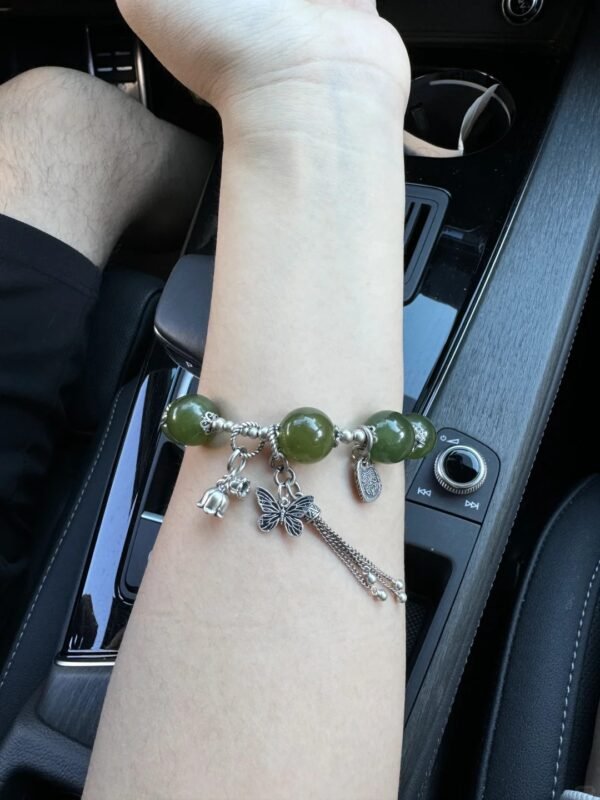 Close-up of Green Grape Xiu Jade bracelet with jade ring and silver butterfly, wood-metal energy blooming